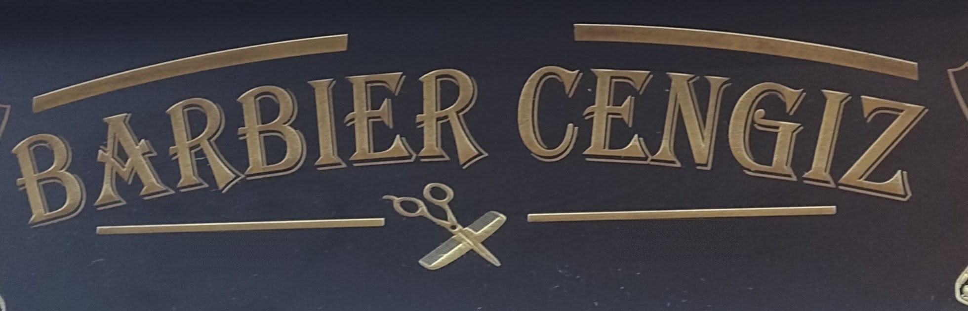 Het goudkleurige naambord BARBIER CENGIZ met schaar en scheermes boven de spiegel in de zaak